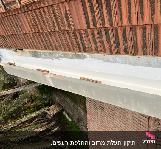 רעפים חומים על גג עם תעלה לבנה
